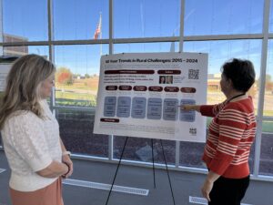 Two women looking at an infographic style information poster in front of a glass wall