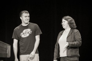 A young man, Colton Foote, and Becky McCray speaking from a large stage.