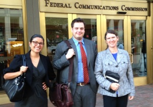 Three people standing in front of a building that says "Federal Communications Commission" 