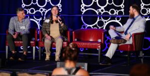 3 people on a main stage at a conference. From left are Tom Gierasimczuk from Resonance and Becky McCray from SaveYour.Town with moderator Will George.