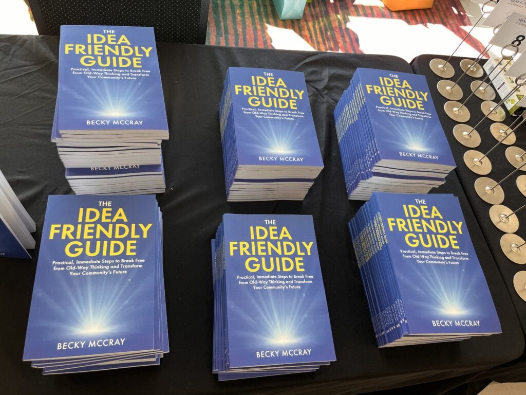200 copies of The Idea Friendly Guide books displayed in multiple stacks on a table at an event
