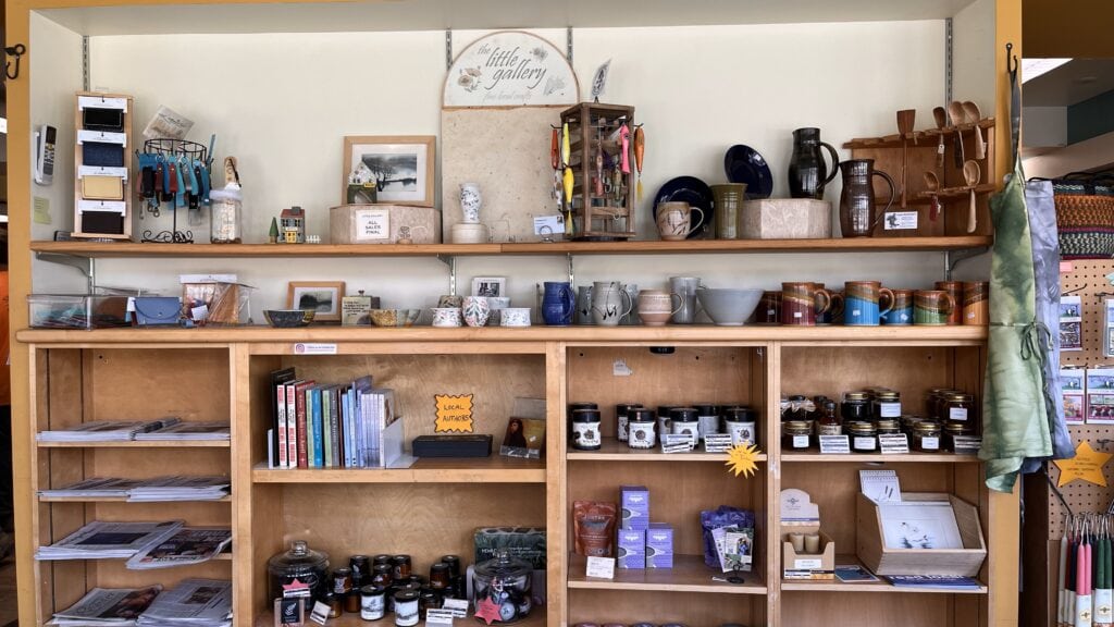 Wooden shelves filled with local crafts like fishing lures and pottery mugs, and art like local prints and books.