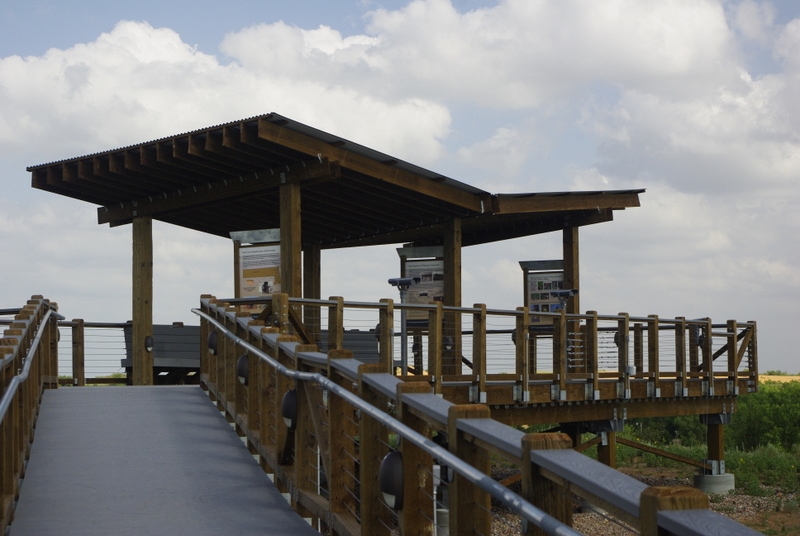 A ramp leads to a shaded wildlife viewing platform in a prairie landscape