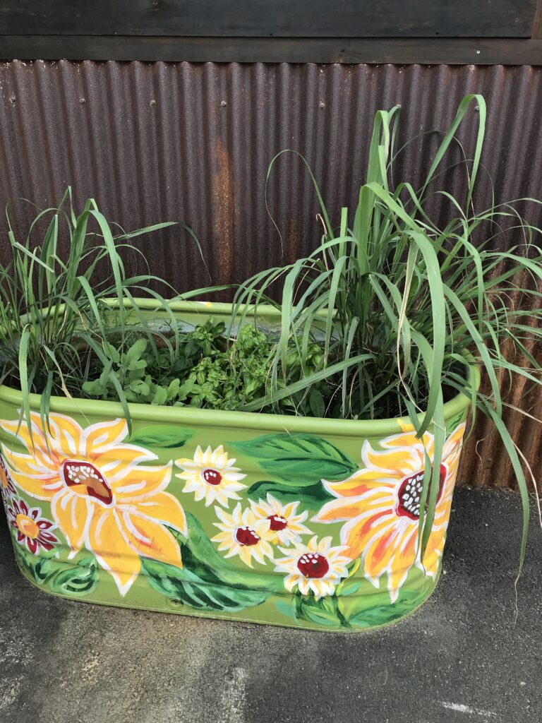 A small metal water tank has been converted to a planter and painted with bright flowers