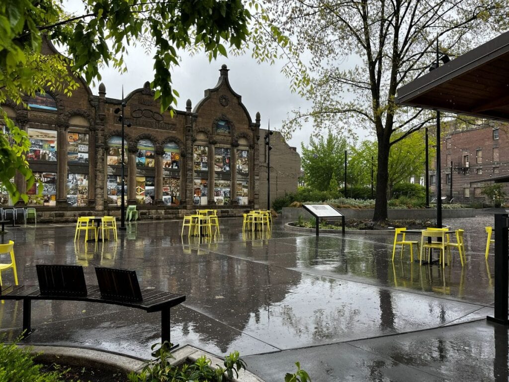 Wide open space downtown with yellow chairs and tables scattered across smooth concrete, with an ornate historic building facade in the background.